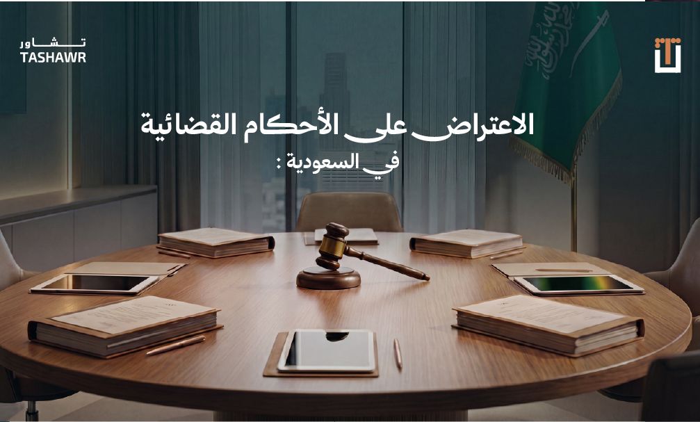 قاعة محكمة فاخرة بطاولة خشبية دائرية وأدوات قانونية وكتب نظام وجهاز لوحي